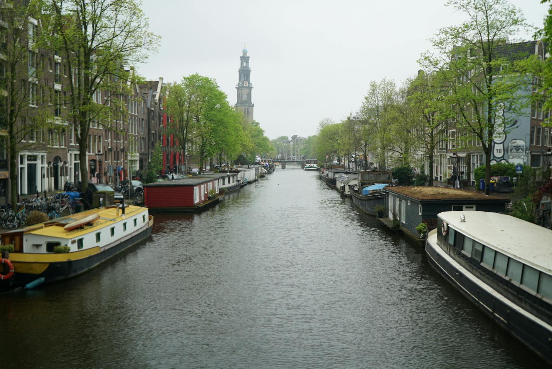 Poranny widok na spokojny kanał w Amsterdamie z barkami i starymi kamienicami
