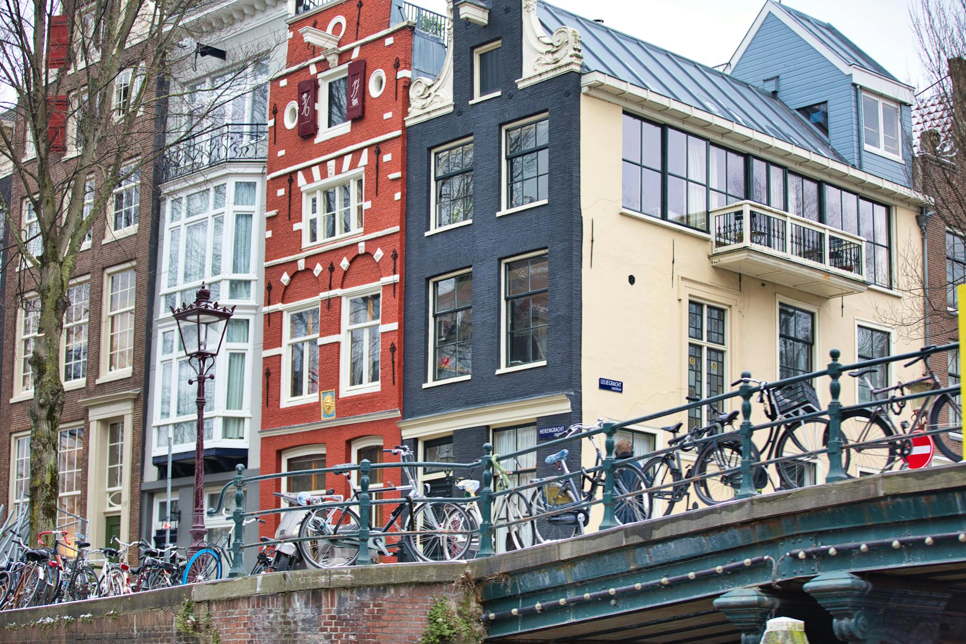 Rowerowy most nad kanałem w Amsterdamie i rząd zabytkowych kamienic