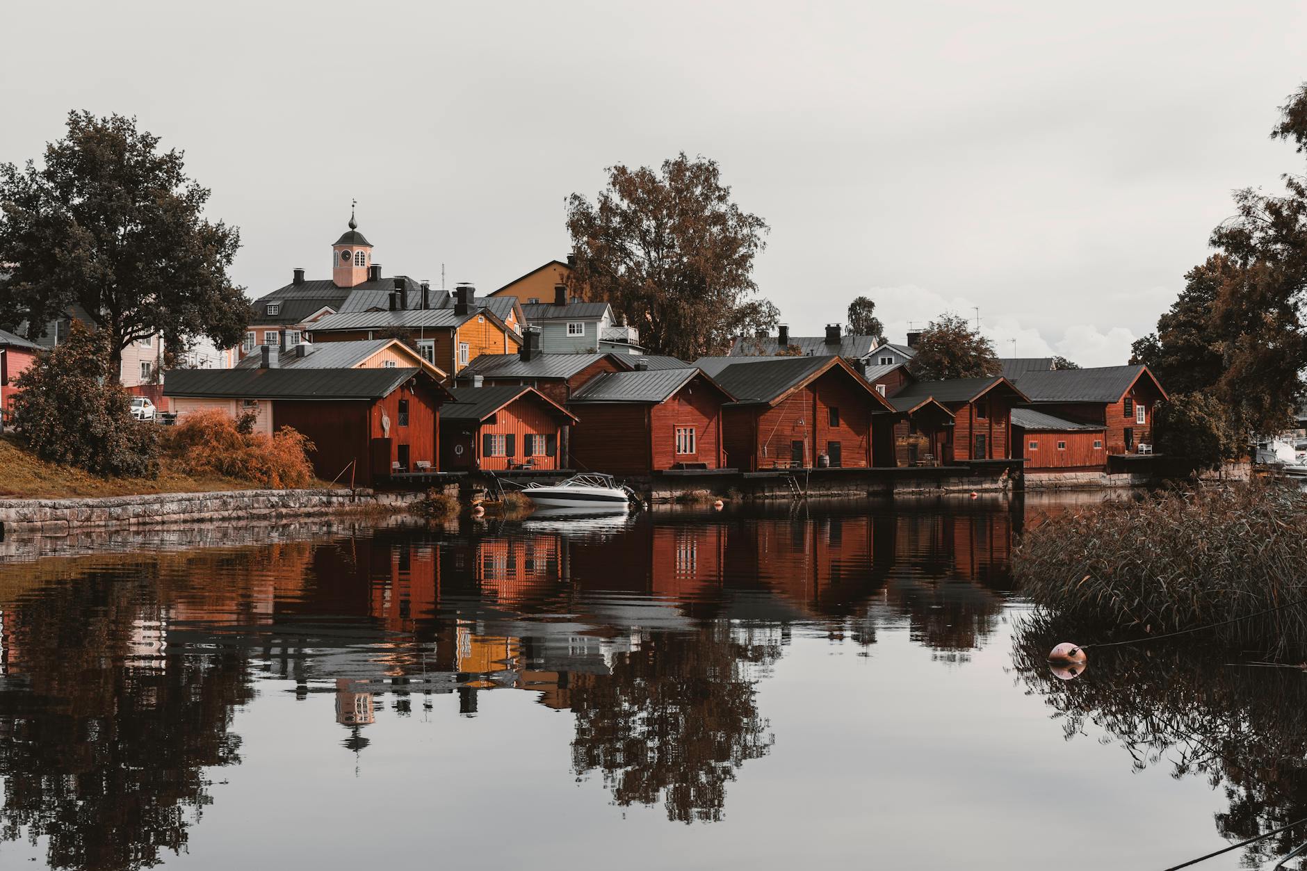Jesienne drewniane domy Porvoo odbijające się w spokojnej rzece