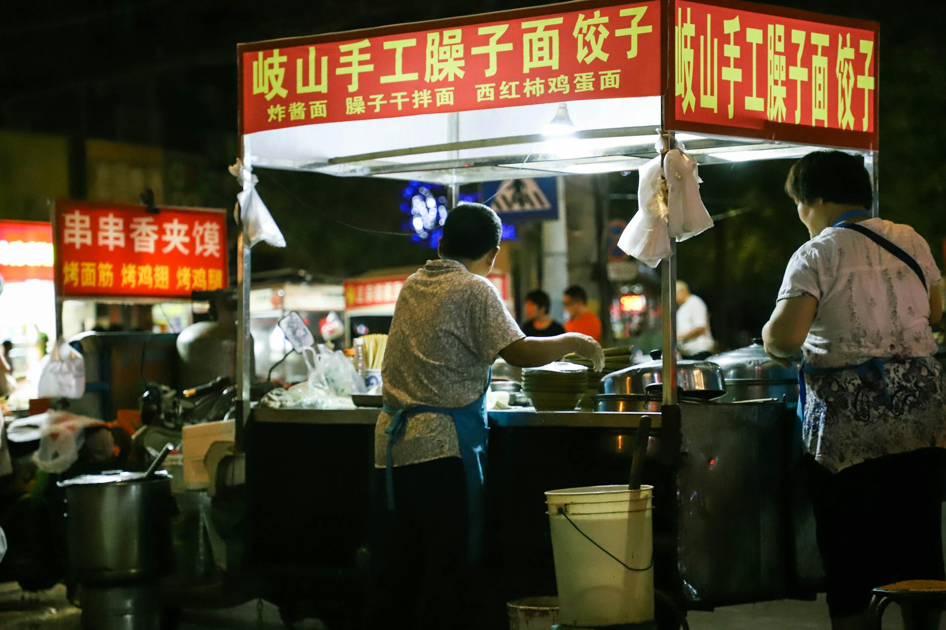 Sprzedawcy street foodu na zatłoczonym nocnym targu w Chinach
