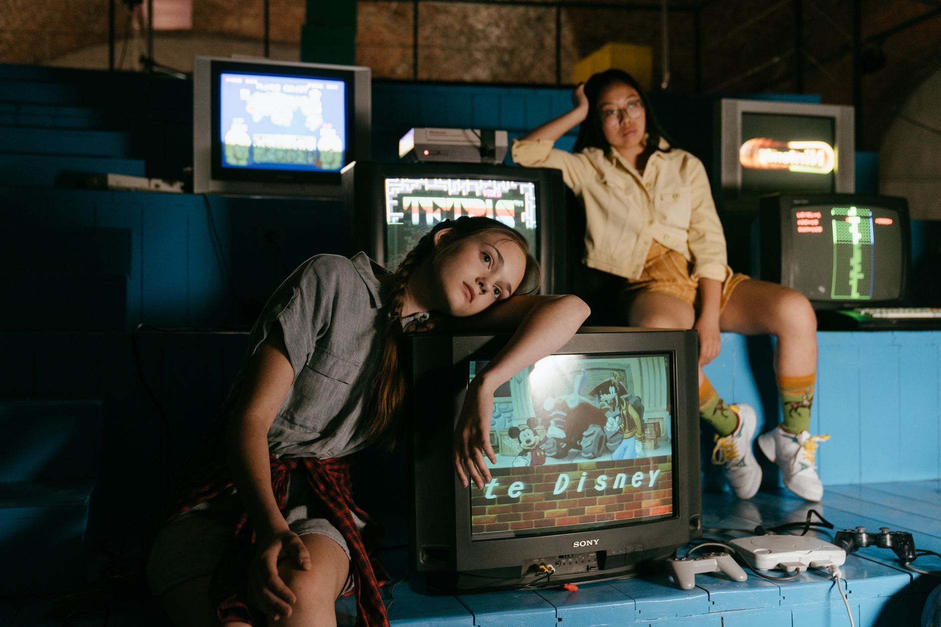 Dwie kobiety grające na retro konsolach przed starymi telewizorami Dwie kobiety grające na retro konsolach przed starymi telewizorami