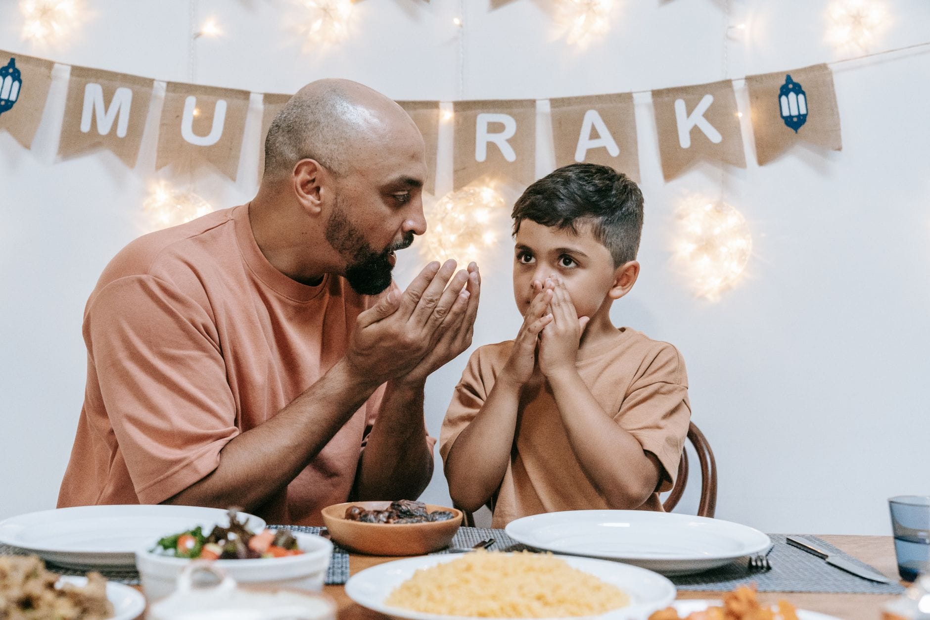 Ojciec i syn modlą się w domu przed wspólnym posiłkiem na Eid