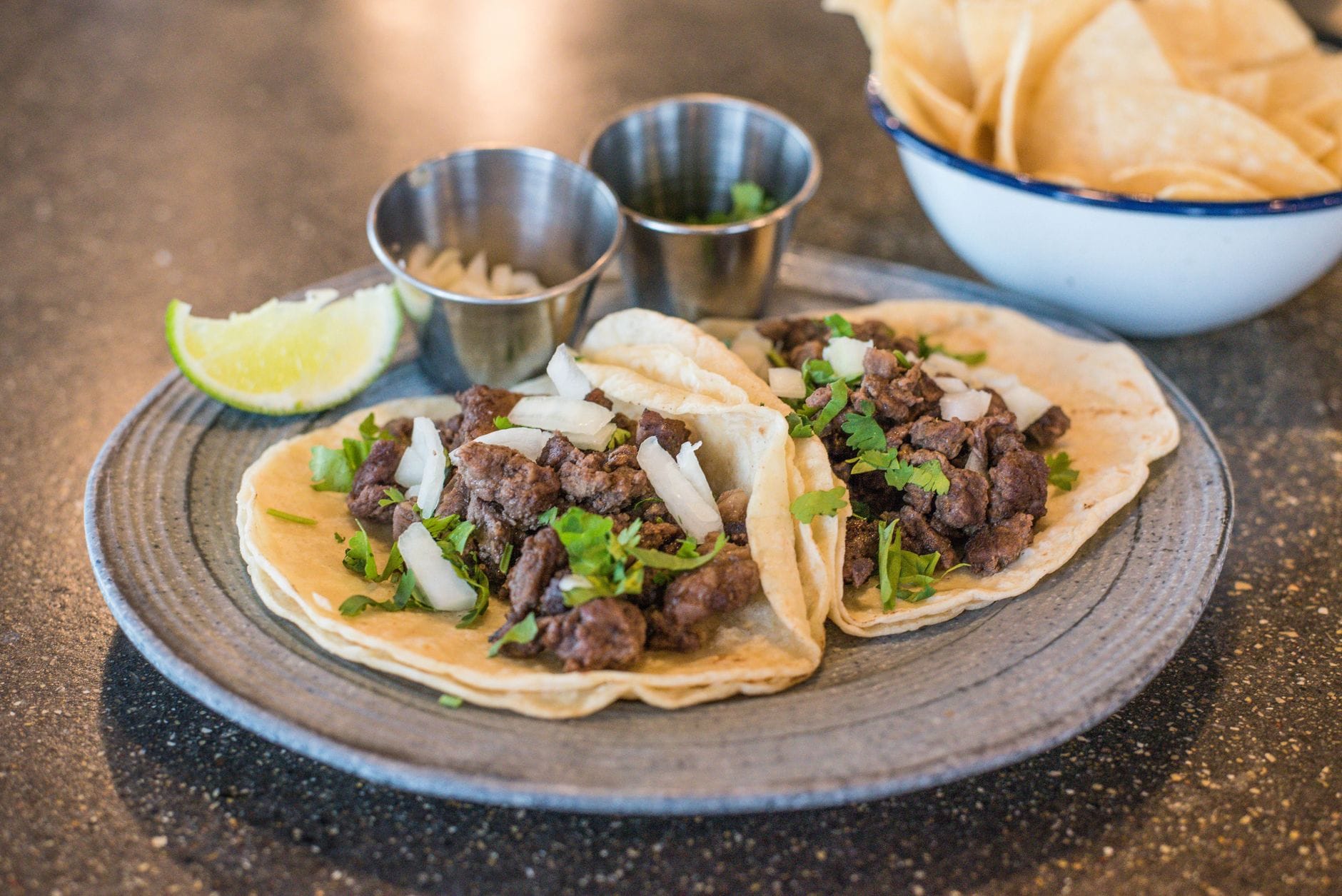 Tacos z wołowiną, kolendrą i limonką na talerzu w meksykańskiej taquerii